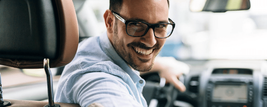 Hombre feliz sonriendo en su coche mejorado